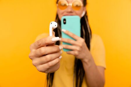 Closeup view of phone and headphones on the yellow background.