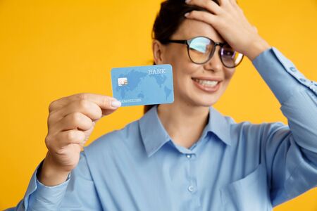 Tired of sale. Lady in glasses holding credit card and put her hand on her head. No money on card.