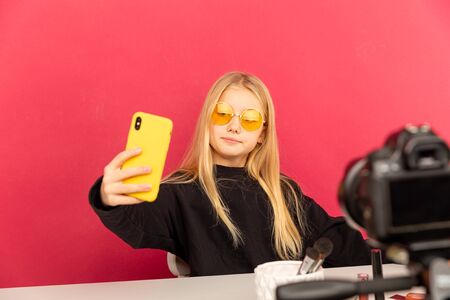 Happy girl at home speaking in front of camera for vlog. Teenage kid working as blogger, recording...