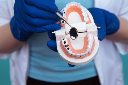 Dentist appointment, dentistry instruments and dental hygienist checkup concept with teeth model dentures and stomatology instruments on dark grey. Regular checkups are essential to oral healthの写真素材