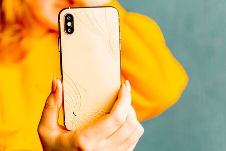 Sad and upset woman holding broken phone isolatedの写真素材