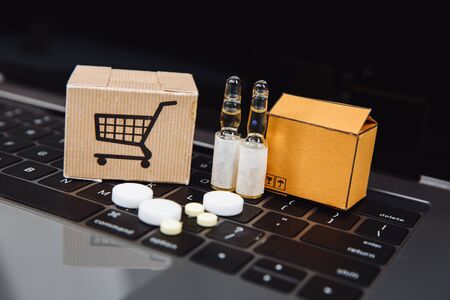 Mini shopping cart full of homeopathic remedies on laptop background. Homeopathy and internet online...