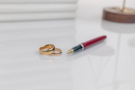Divorce concept. Golden rings on the table with wooden hammer and money.の写真素材