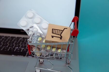 Mini shopping cart full of homeopathic remedies on laptop background. Homeopathy and internet online shopping concept.の写真素材