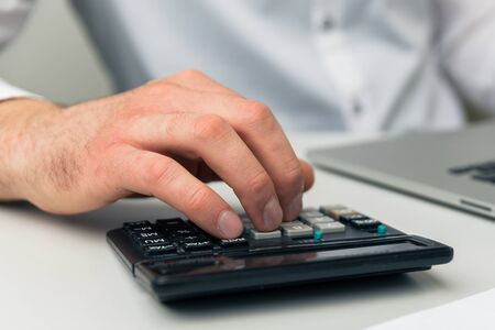 Accounting at home at quarantine. Man working on computer and calculator.