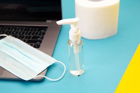Laptop with protective face mask, chemical spray for disinfectionand a stock of toilet paper for the...