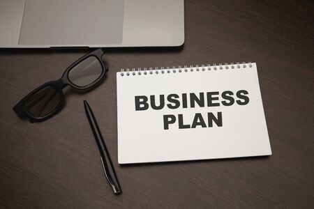 Workplace, laptop, pen and notepad with business planの写真素材