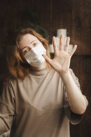 Quarantine stay at home. Bored and worried woman working alone at home in the medicine mask.の写真素材