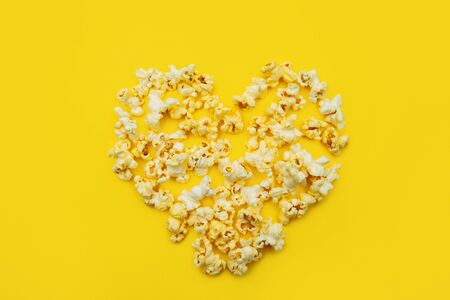 Love Cinema concept of popcorn arranged in a heart shape on yellow background.の写真素材