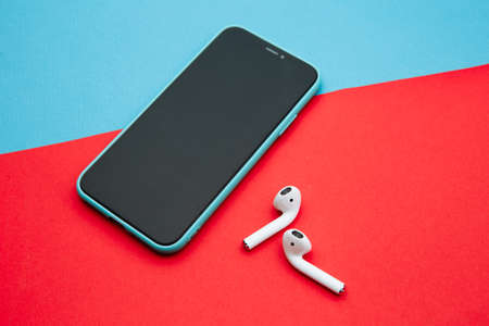 Tula Russia 16.01.20: Apple AirPods wireless Bluetooth headphones for Apple iPhone. New Apple Earpods Airpods on a blue background. Copy spaceのeditorial素材