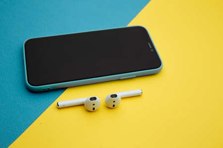 Tula Russia 16.01.20: Apple AirPods wireless Bluetooth headphones for Apple iPhone. New Apple Earpods Airpods on a blue background. Copy spaceのeditorial素材