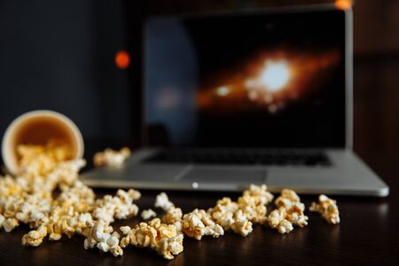 Popcorn in bowl and laptop playing movie. Entertainment conceptの写真素材