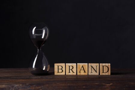 Brand communication for product and service advertising, Hourglass or sandglass near wooden cube...