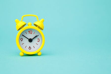 Yellow alarm clock Isolated on blue trendy background. Rest hours time of life good morning night wake up awake conceptの写真素材