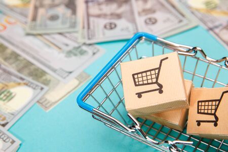 Money banknotes dollar and shopping basket with boxes on blue background.Easy shopping with finger...