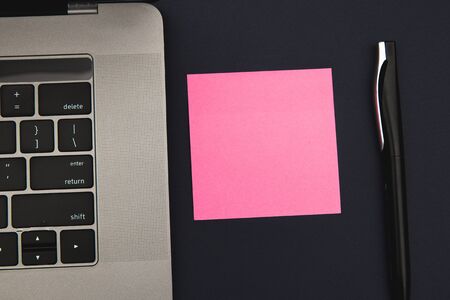 Laptop with sticker, space for text, and pen on a dark blue background. View from above. Business and remote work conceptの写真素材