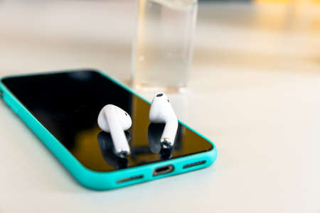 Tula Russia 13.04.2020 Phone with airpods on the desk isolated.