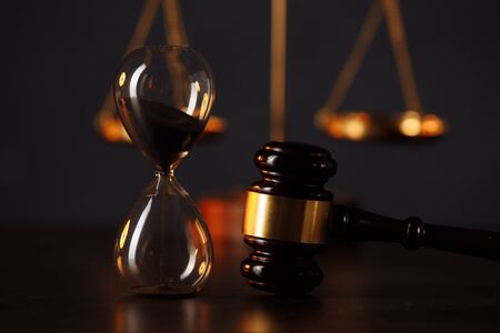 Judges gavel, scales of justice and hourglass in dark room. Law and justice concept.