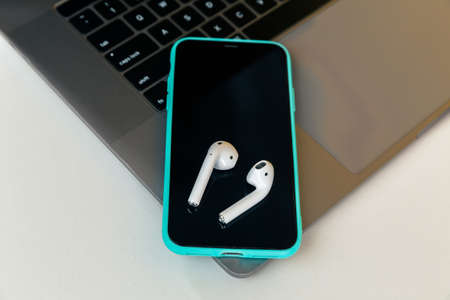 Tula Russia 13.04.2020 Phone with airpods on the desk isolated.