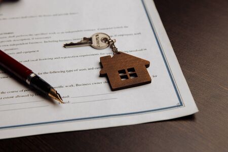 House keys and money on a signed contract of house sale. Focus on keys.の写真素材