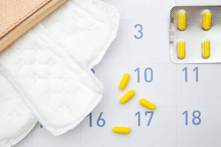 Pink beautician with daily cotton sanitary pads and hormonal contraceptive on calendar. Travel...