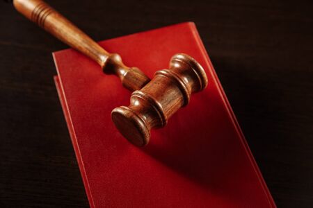 law book with a judges gavel resting on top of the pages in a courtroom or law enforcement office.