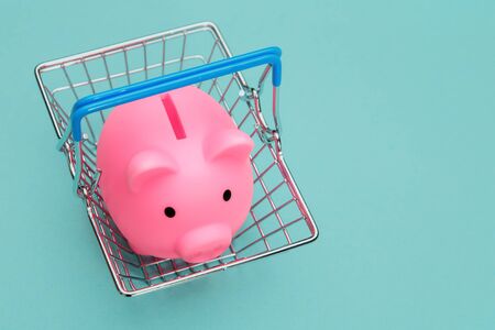 Supermarket basket with piggy bank on a blue background. Shopping concept.の写真素材