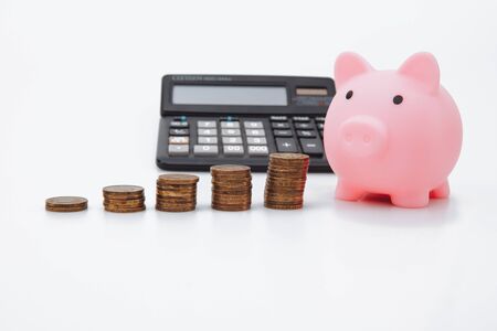 Coin tower, calculator and piggy bank on white background, close up. Money saving concept.の写真素材