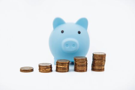 Finance Savings, save money for future investments and for emergency use concept. A blue piggybank and coin tower on white background.の写真素材