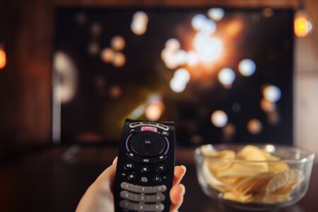 Whatching Tv and eating chips from glass bowl at home conceptの写真素材