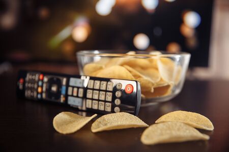 Snacks and Tv remote control at the tableの写真素材