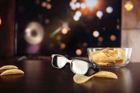 Chips and 3D glasses at the desk infront of big Tv set