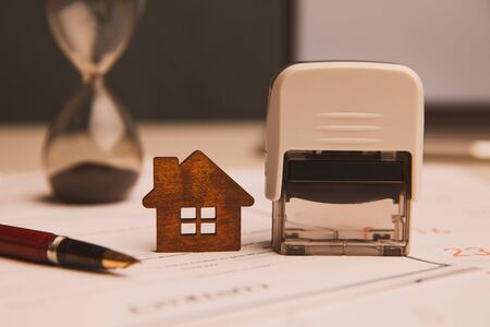Businessman hands signing documents file paperwork financial or property mortgage real estate investment business on desk office with chart report document contact customer with wooden house models.の写真素材