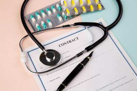 Life planning concept with health insurance form, stethoscope, pen and pillsの写真素材