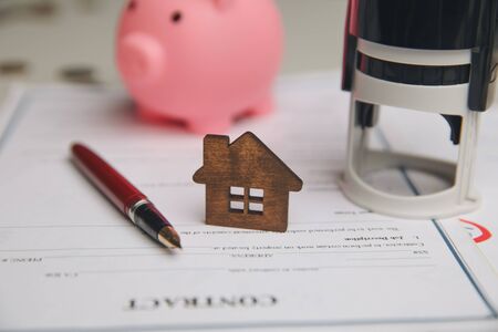 Businessman hands signing documents file paperwork financial or property mortgage real estate investment business on desk office with chart report document contact customer with wooden house models.の写真素材
