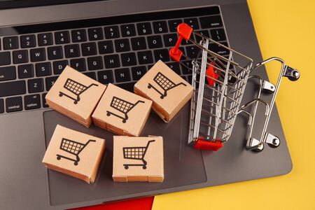 Online shopping concept. Five boxes on laptop and shopping cart isolated on colorful backgroundの写真素材