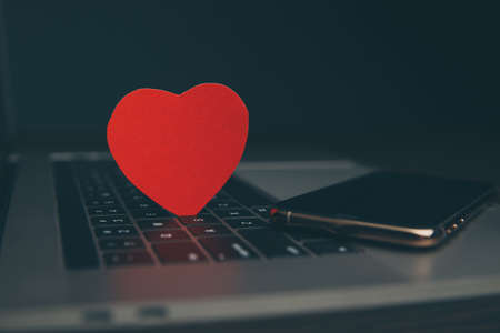 Computer with red hearts on table close up.の写真素材
