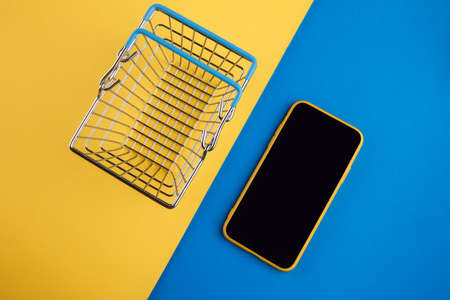 Online shopping concepts with shopping basket and smartphone on yellow red background. Ecommerce market. Transportation logistic. Business retailの写真素材