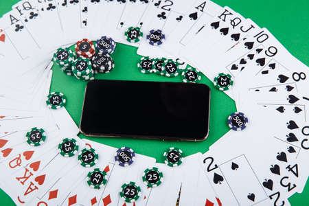 Online casino concept, playing cards, dice chips and smartphone with copyspace on the green table. Top viewの写真素材