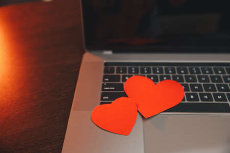 Computer with red hearts on table close up.の写真素材