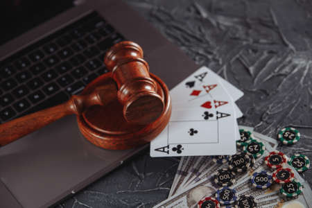 Law and rules for online gambling concept, judge gavel with playng cards and money banknotes on...