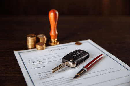 Contract for car purchase, stamp, pen and car key on wooden tableの写真素材