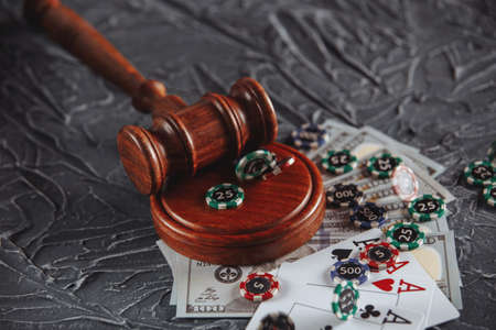 Legal rules for online gambling concept. Wooden gavel, money banknotes and playing cards on grey backgroundの写真素材