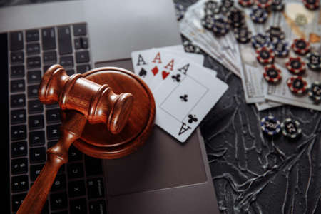 Judge wooden gavel and playing cards on computer keyboard, legal rules for online gambling conceptの写真素材