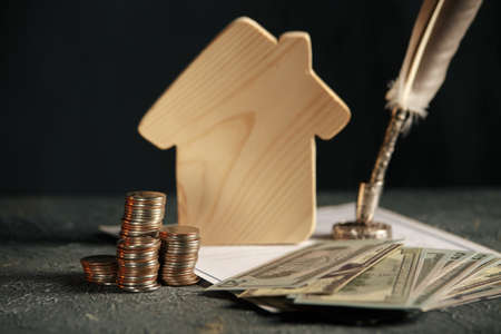 Miniature house with money and tax papers