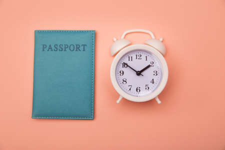 Time to travel. Passport and clock on pink background. Top viewの写真素材