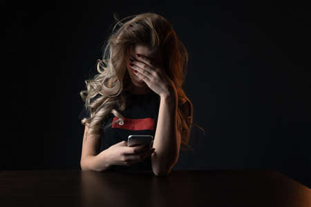 Closeup picture of frustrated girl, young woman being a victim of bullying onlineの写真素材