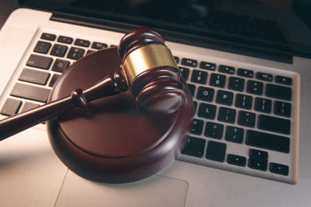 Gavel with books and scales on brown background