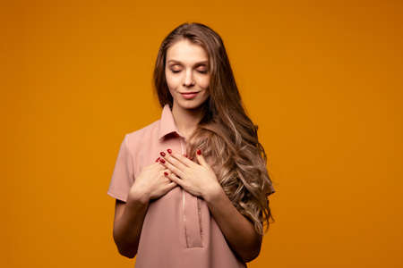 Portrait of nice glad young woman, thankful pretty girl with her hands on her chest