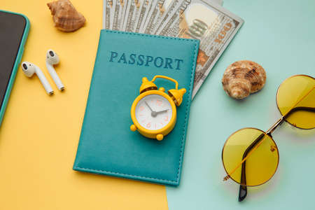Summer vacation concept. Sunglasses, smartphone and passport with money banknotes on blue yellow background. Close-upの写真素材